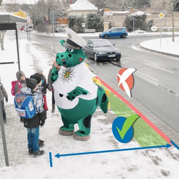 Es ist Winter. Etwas Schnee liegt auf dem Gehweg. Poldi steht gemeinsam mit Kindern an einer Bushaltestelle.